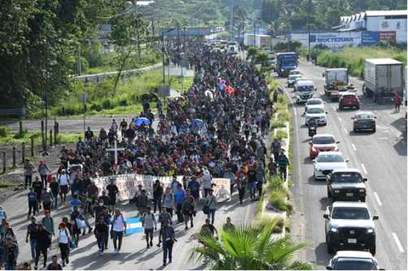 Un gran grupo de personas caminando por una carretera.