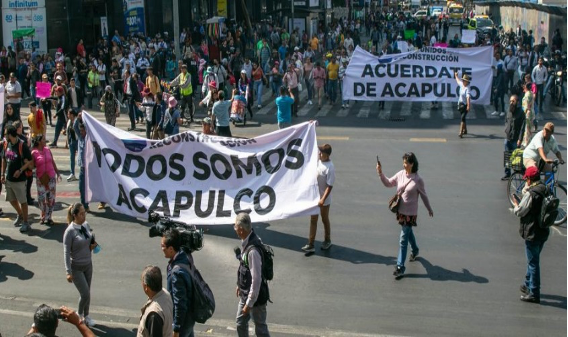 Un grupo de personas caminando por una calle sosteniendo pancartas.