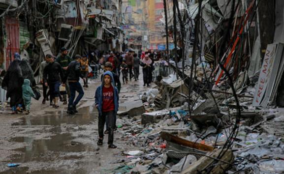 La gente camina por una calle en una zona destruida.