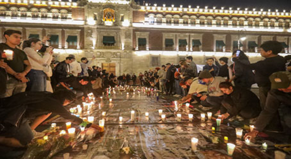 Un grupo de personas colocando velas en el suelo frente a un edificio.