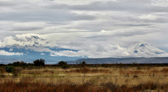 Una cadena montañosa con montañas cubiertas de nieve al fondo.