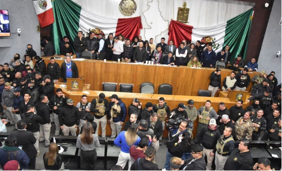 Un grupo de personas paradas frente a una bandera mexicana.