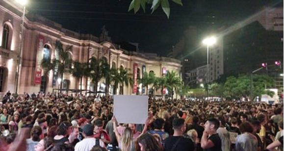 Una multitud de personas paradas frente a un edificio por la noche.