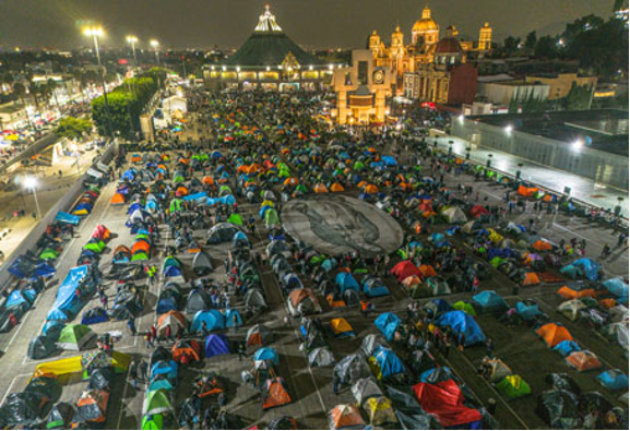 Un gran grupo de personas sentadas en el suelo por la noche.