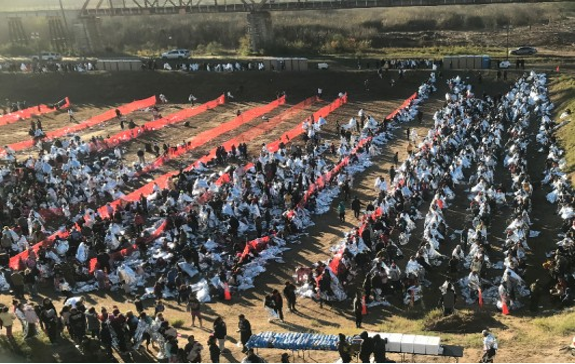 Un gran grupo de personas está reunida frente a un puente.