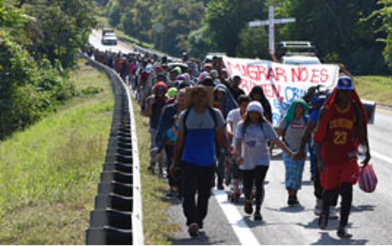 Un grupo de personas caminando por una calle con una pancarta.