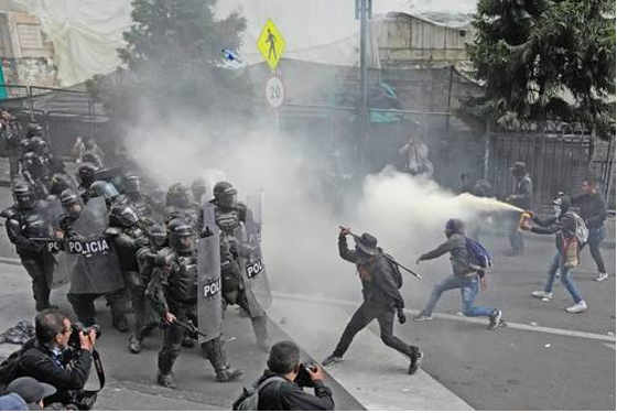 Un grupo de policías antidisturbios en una calle con humo saliendo de la boca.