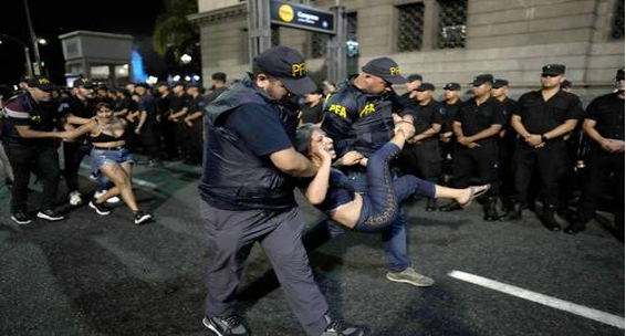 Una mujer es llevada por agentes de policía por la calle.