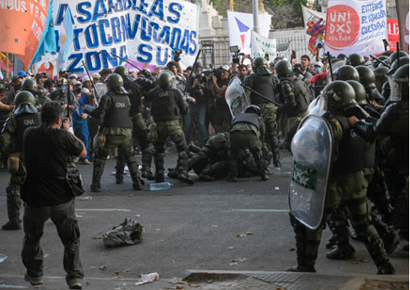 Un grupo de policías antidisturbios en una calle con una pancarta.