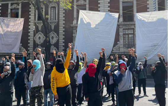 Un grupo de personas sosteniendo pancartas frente a un edificio.