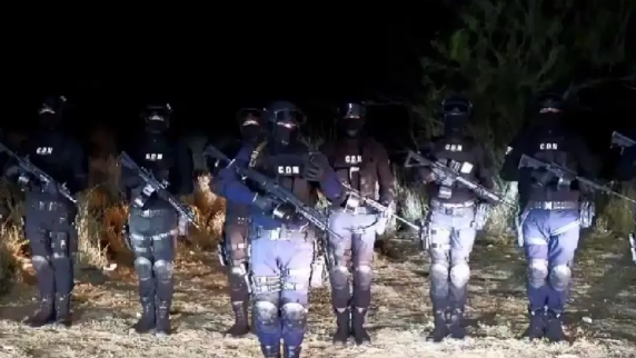 Un grupo de hombres armados parados en un campo por la noche.