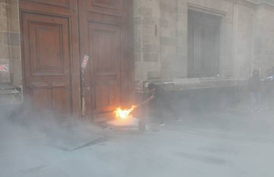 Un hombre está quemando una puerta frente a un edificio.