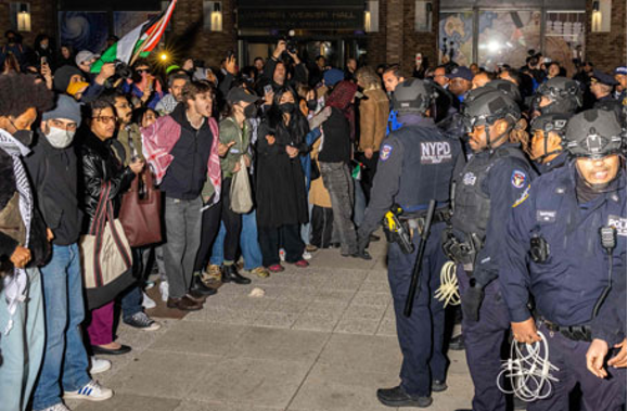 Manifestantes frente a una fila de agentes del Departamento de Policía de Nueva York durante una manifestación nocturna.