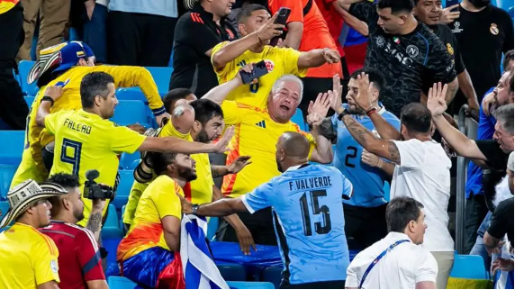 Varios aficionados al fútbol que vestían camisetas amarillas y azules entablaron una acalorada discusión con espectadores vestidos con otras prendas en los asientos del estadio. Un individuo con camiseta azul, el número 15, intenta intervenir.