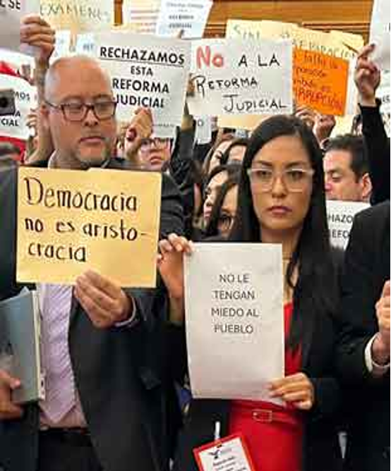 Un grupo de personas con carteles de protesta, entre ellos "Democracia no es aristocracia" y "No le tengan miedo al pueblo", expresando su oposición a la reforma judicial.