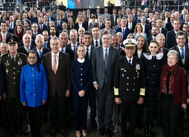 Un grupo grande de personas, entre ellas personal militar y funcionarios, posan juntos para una foto grupal formal en un interior.