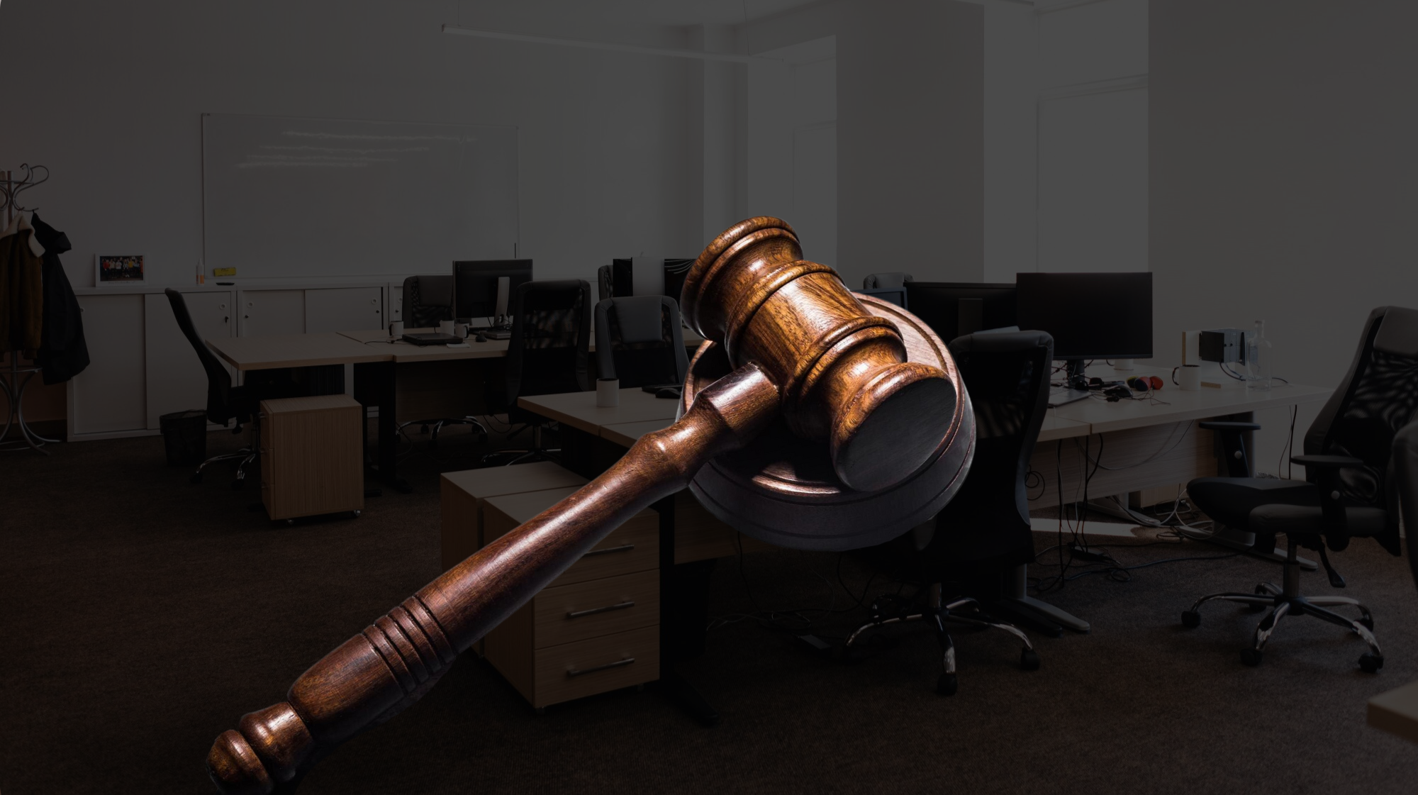Un mazo de madera se exhibe de forma destacada sobre un espacio de trabajo de oficina vacío con escritorios, sillas y computadoras.