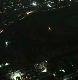 Vista aérea nocturna de una ciudad con edificios y calles iluminados.