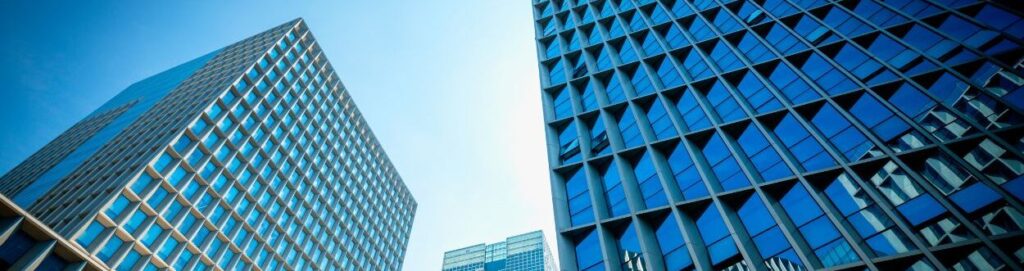 Un primer plano de dos edificios con un cielo azul  en digitalizaciÃ³n detrÃ¡s de ellos.