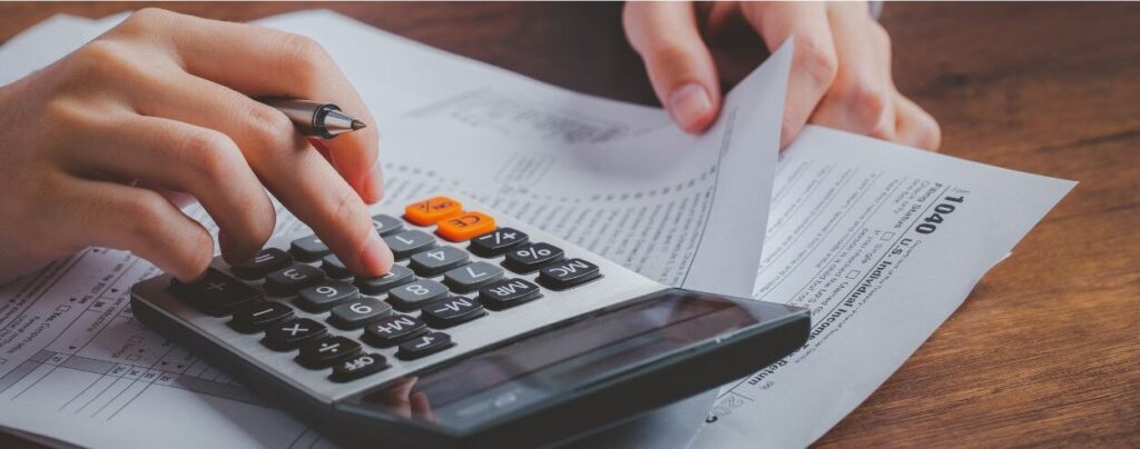 Una persona usa una calculadora mientras revisa los documentos tributarios, asegurÃ¡ndose de que cada detalle estÃ© alineado con las Ãºltimas pautas tributarias de recaudaciÃ³n