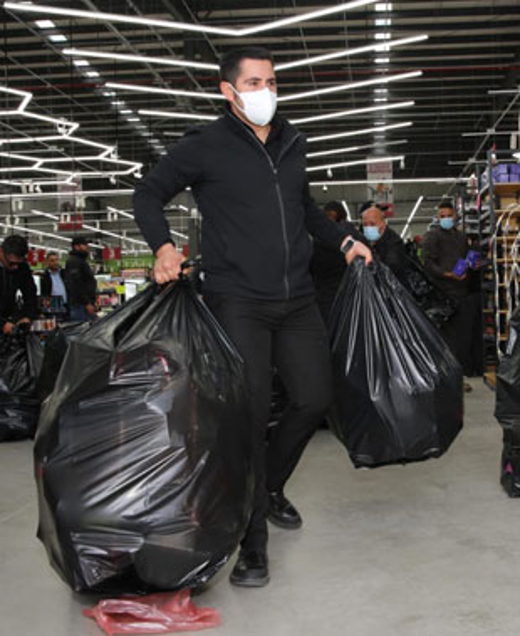 Una persona con máscara lleva dos grandes bolsas de basura negras dentro de una tienda.