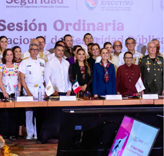 Un grupo de personas, incluidos funcionarios uniformados, se encuentra frente a una pancarta de la conferencia con banderas y micrófonos sobre la mesa.