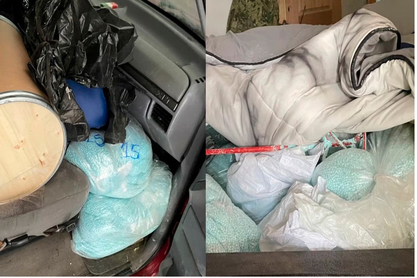 Automóvil lleno de grandes bolsas con artículos azules y blancos y un colchón o manta enrollada.