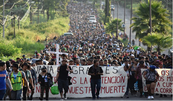 Un grupo de personas caminando por una calle con una pancarta.