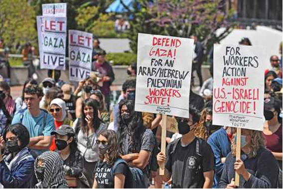 Personas en una manifestación con carteles de apoyo a Gaza y críticas a las políticas de Estados Unidos e Israel.