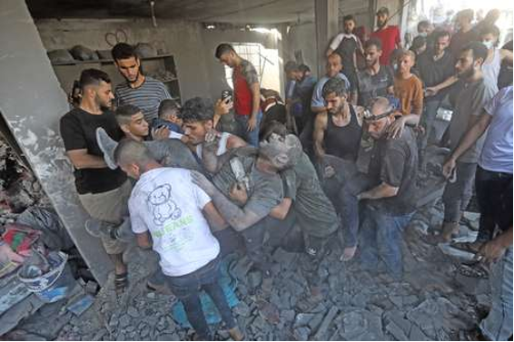 Un grupo de personas está reunida alrededor de un edificio en ruinas.