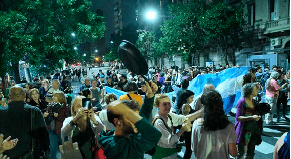 Una multitud de personas paradas en una calle por la noche.