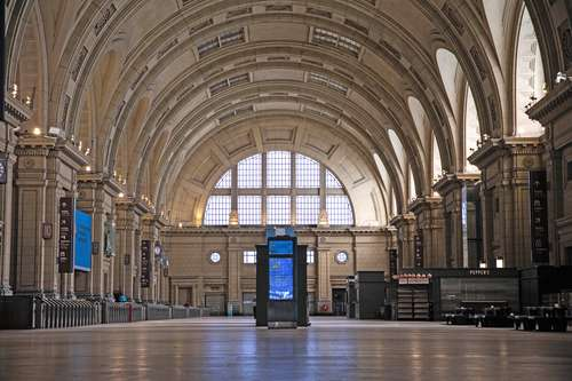 Interior de un gran vestÃ­bulo de estaciÃ³n de tren con altos techos abovedados, grandes ventanales y un quiosco de informaciÃ³n en el centro.