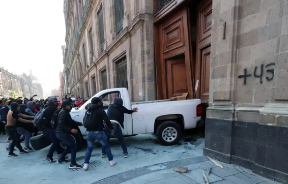 Un grupo de personas empuja un camión hacia un edificio.