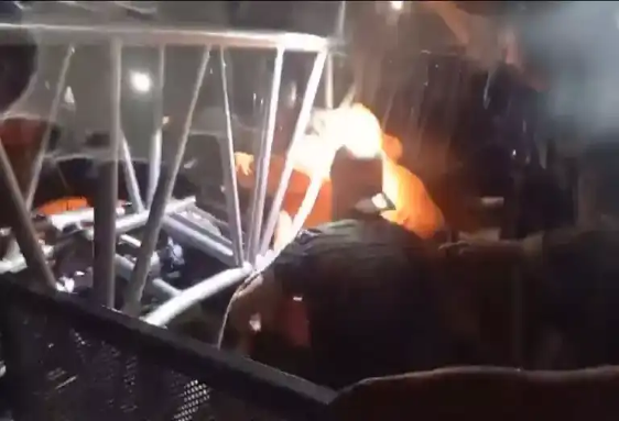 Personas en situación de emergencia trabajan en una estructura metálica por la noche, parcialmente iluminada por luces.