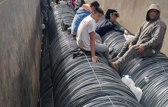 Individuos sentados sobre grandes bobinas de cable.