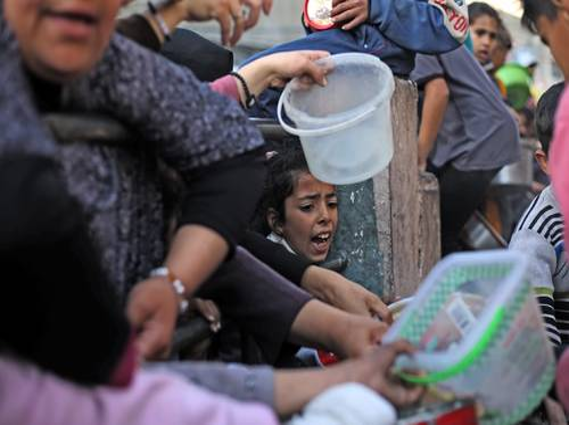 Una joven se acerca a la multitud, posiblemente para pedir ayuda o suministros.