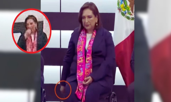 Una mujer está sentada frente a una bandera mexicana.
