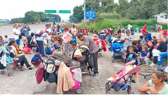 Un grupo de personas sentadas al costado de la carretera.