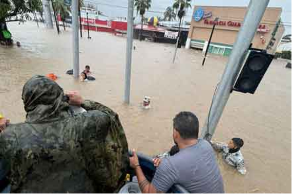 Se está rescatando a personas de una calle inundada; una persona con vestimenta militar supervisa la operación de rescate desde un punto de observación más alto.
