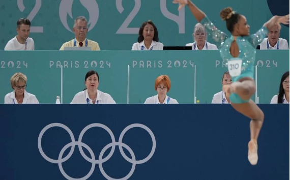 Una gimnasta realiza una rutina frente a un panel de jueces en los Juegos OlÃ­mpicos de ParÃ­s 2024.