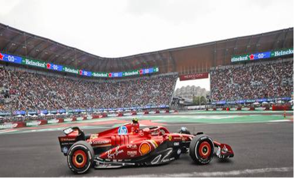 Un coche rojo de Fórmula 1 corre en una pista rodeado de una multitud que lo anima en un estadio.