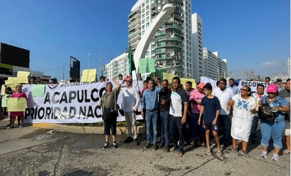 Un grupo de personas con carteles frente a un edificio.