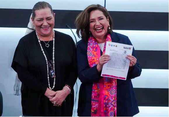 Dos mujeres paradas una al lado de la otra sosteniendo papeles.