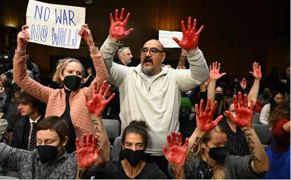 Un grupo de personas sosteniendo carteles con sangre en las manos.