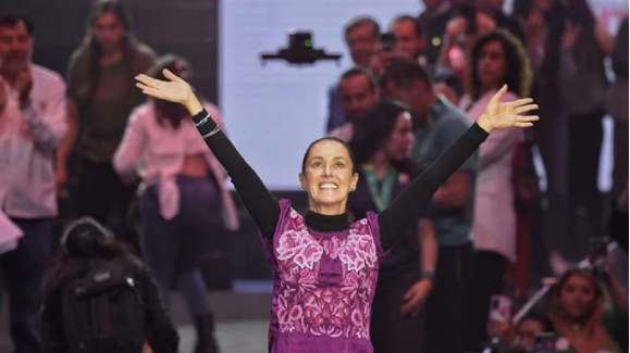Una mujer con los brazos extendidos frente a una multitud.