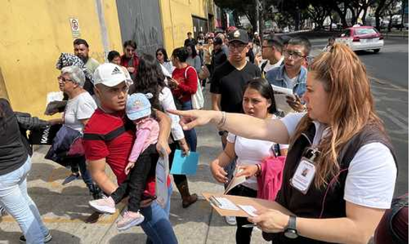 Un grupo de personas paradas en fila en una acera.