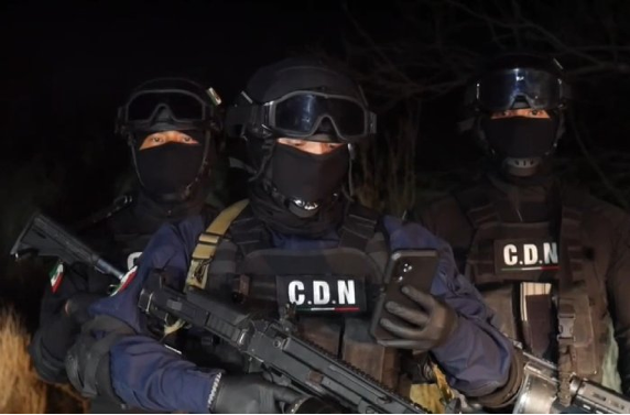 Tres policías mexicanos de pie por la noche con armas de fuego.