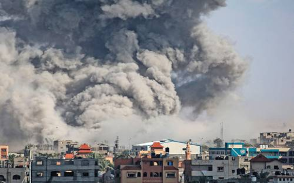 Gran columna de humo que se eleva sobre un paisaje urbano con edificios coloridos, lo que indica una explosión o incendio importante en una zona urbana.