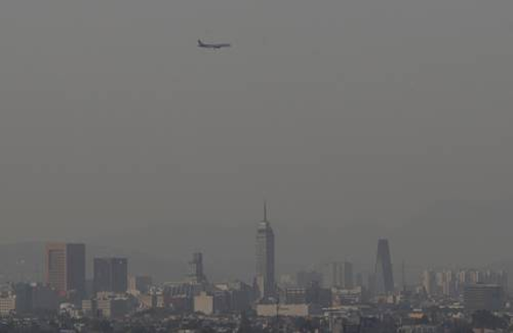 Un avión sobrevuela una ciudad con edificios al fondo.