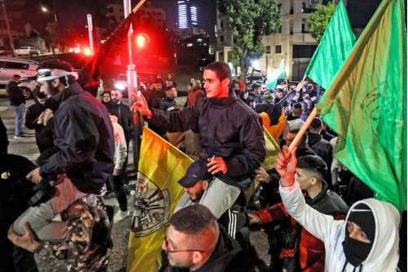 Un grupo de personas sosteniendo banderas verdes en la calle.